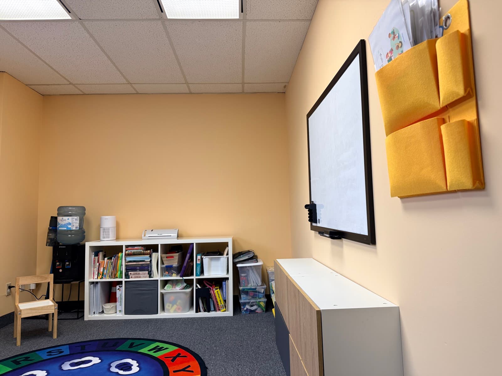 Learning room with whiteboard, felt wall organizers, and shelves of books and materials