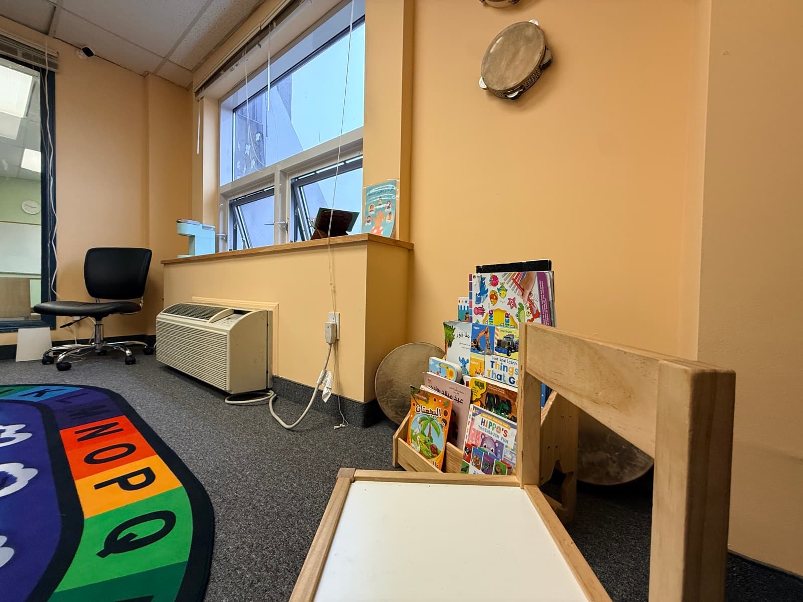 Reading corner with a book display, tambourine, and alphabet rug